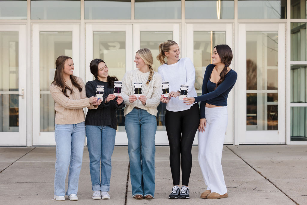 Five women standing together holding AWAREties in front of a building