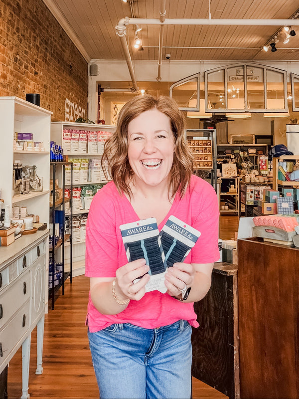 Woman holding socks in a store with brick walls and wooden floors
