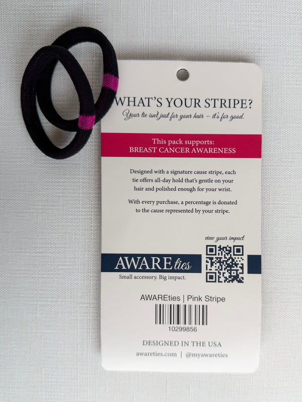 Black hair tie with pink accent on a 'Aware Lies' label for breast cancer awareness on a light gray background