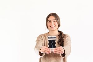 Woman holding a product with a visible brand logo against a white background